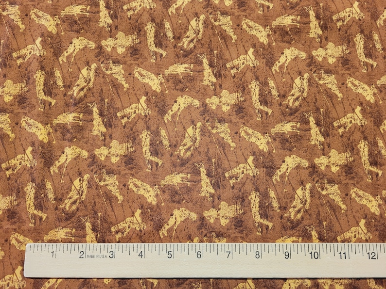 K&ouml;nnte beinhalten: Brauner Stoff mit einem goldenen Silhouettenmuster von Golfern, die ihre Schl&auml;ger schwingen. Der Stoff ist strukturiert und hat einen rustikalen Look.