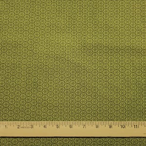 May include: Close-up of a green fabric with a repeating floral pattern. The fabric has a ruler with inch measurements along the bottom. The pattern is a series of small, six-petal flowers arranged in a honeycomb design.