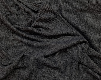 May include: Dark gray fabric with a ribbed texture, draped and folded. The material has a subtle, heathered appearance, with variations in tone. The fabric's surface is soft and pliable, with visible vertical lines.