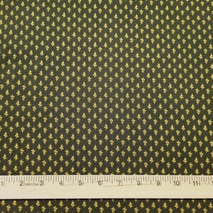 May include: A dark green fabric with a repeating pattern of small gold fleur-de-lis. A ruler is placed at the bottom of the image, showing measurements in inches.