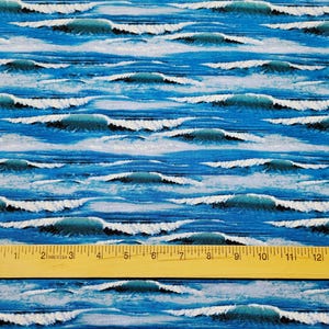 May include: A close-up of a blue and white fabric with a repeating pattern of ocean waves. A wooden ruler is placed on top of the fabric to show the scale.