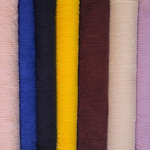 May include: A vertical shot of several rolls of fabric in various colors. The colors include light pink, blue, navy, yellow, burgundy, cream, and lavender. The fabric has a ribbed texture.