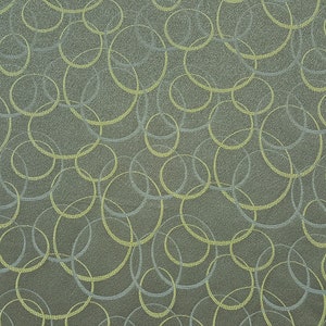May include: A close-up of a fabric with a repeating pattern of overlapping circles in shades of green and gray.