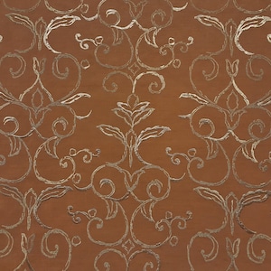 May include: A brown fabric with a silver metallic pattern of swirling vines and leaves.
