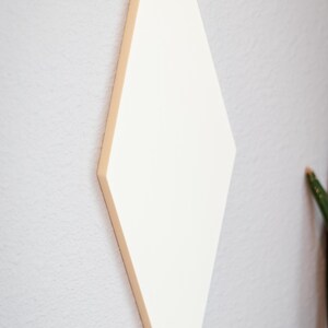 Puede incluir: Decoraci&oacute;n de pared en forma de rombo de color crema. La pieza de arte geom&eacute;trico est&aacute; montada en una pared gris claro. El rombo tiene un borde biselado y est&aacute; ligeramente inclinado hacia el espectador.