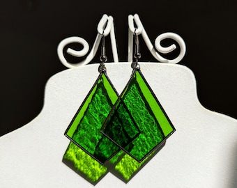 May include: A pair of green glass earrings with a diamond shape. The earrings are hanging from silver hooks.