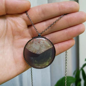 May include: A silver chain necklace with a round pendant featuring a slice of agate with a white and purple color scheme.