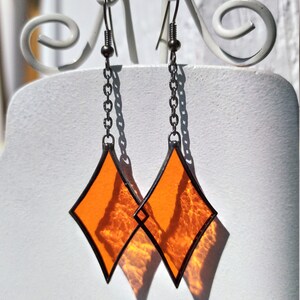 Op de afbeelding: Een paar oranje ruitvormige glas-in-lood oorbellen met zilveren kettingen en haken.