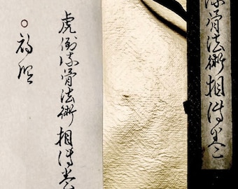 May include: A close-up of a white paper scroll with black calligraphy. The text reads "A long time ago, I was a tree". The scroll is attached to a black and white wooden box.