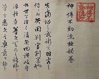 May include: A close-up of a vintage Japanese scroll with black calligraphy on a light beige background. The scroll features the text "神傳不動流極秘卷", which translates to "Secret Scroll of the Divine Transmission Immovable Flow".