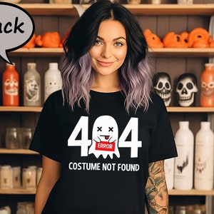 May include: Black t-shirt with a Halloween-themed graphic. The design features the number "404" with a ghost and the words "COSTUME NOT FOUND" in white. The shirt is a classic crew neck style.