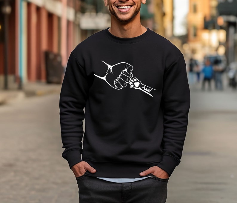 May include: Black sweatshirt with a white graphic of a human hand and a dog paw bumping fists. The text "Axel" is below the graphic.