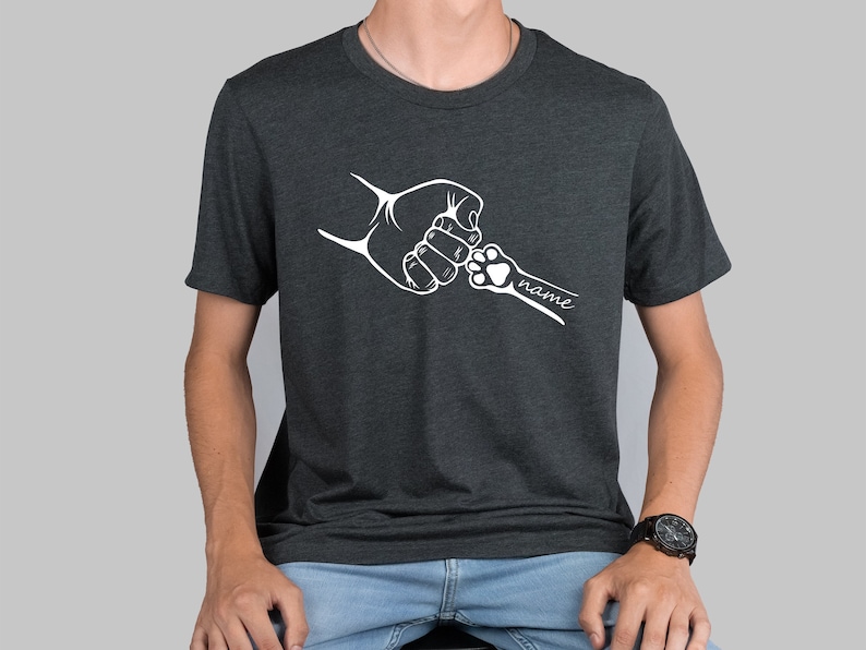 May include: A dark gray t-shirt with a white graphic of a human hand and a paw shaking hands. The text "name" is below the graphic.