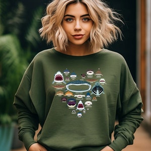 May include: A green sweatshirt with a heart-shaped design featuring various types of sharks. The design includes the names of each shark species.