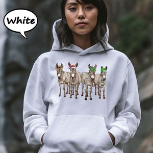 May include: White hooded sweatshirt with a graphic of five donkeys decorated with Christmas lights and festive hats. The word "White" is in a speech bubble. The donkeys are wearing Santa hats, green hats, and scarves.