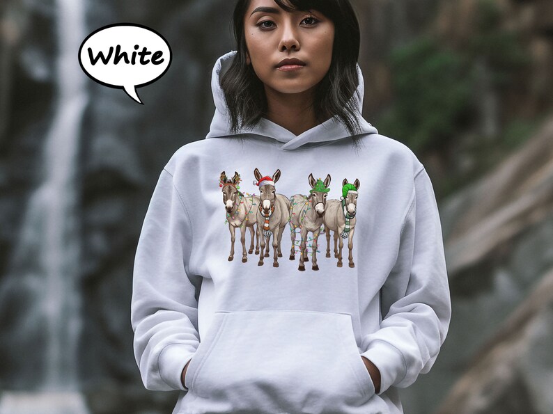 May include: White hooded sweatshirt with a graphic of five donkeys decorated with Christmas lights and festive hats. The word "White" is in a speech bubble. The donkeys are wearing Santa hats, green hats, and scarves.