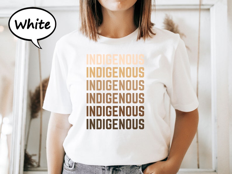 Pu&ograve; includere: T-shirt bianca con la scritta "INDIGENOUS" stampata in un gradiente di tonalit&agrave; marroni. La parola &egrave; ripetuta verticalmente sei volte. Una nuvoletta con la parola "White" si trova nell'angolo in alto a sinistra.