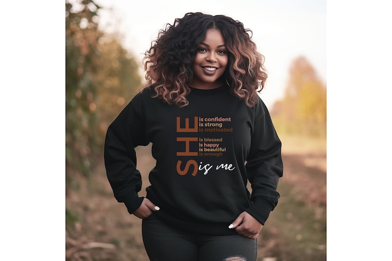 Op de afbeelding: Zwart sweatshirt met de tekst "SHE is confident is strong is motivated is blessed is happy is beautiful is enough is me" gedrukt in bruin en wit.