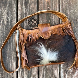 brown cowhide purse with fringe, crossbody or shoulder, zipper and snap closure. Hair on hide large bag with back pocket.