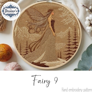 Könnte beinhalten: Handgesticktes Feen-Design in einem Holzreifen. Das Kunstwerk zeigt eine Fee mit langen, fließenden Haaren und Flügeln, die in einer Waldszene mit Bergen und Bäumen steht. Der Text "Fairy 9" befindet sich darunter.