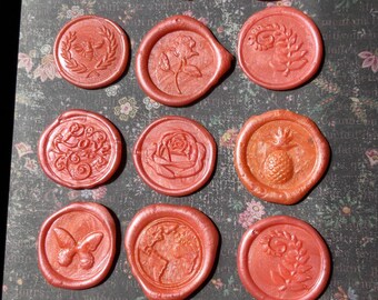 May include: A collection of 18 red wax seals with various designs, including a butterfly, a pineapple, a rose, a bee, a globe, and a fleur-de-lis.