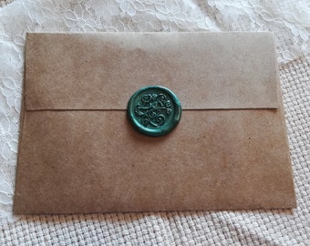 May include: A brown paper envelope with a green wax seal. The seal has a decorative design.