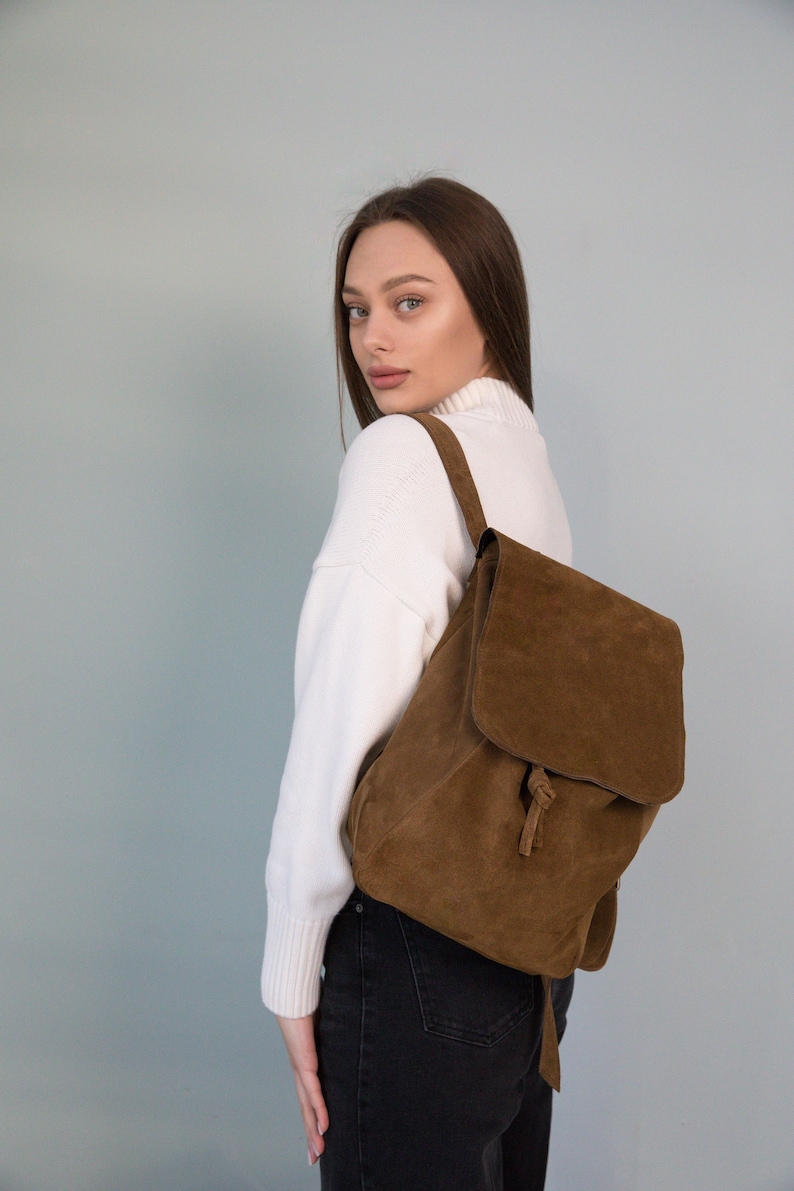 A young woman with a stylish small suede backpack.