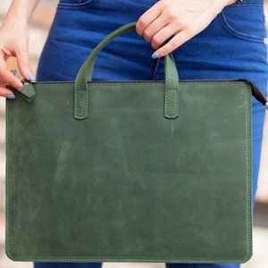 Puede incluir: Un bolso para port&aacute;til de cuero verde oscuro con cierre de cremallera y dos asas.