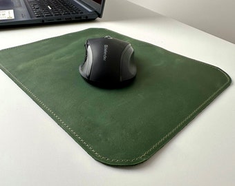 Könnte beinhalten: Ein grünes Leder-Mauspad mit einer schwarzen Computermaus darauf. Das Mauspad hat einen genähten Rand.