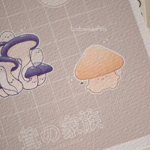 Puede incluir: Un hongo marr&oacute;n claro con un tallo blanco y una cara sonriente. El hongo est&aacute; sobre un fondo marr&oacute;n claro con un patr&oacute;n de cuadr&iacute;cula. El texto "LudowikasPins" est&aacute; en la esquina superior derecha de la imagen. El texto "春の家族" est&aacute; en el centro inferior de la imagen.