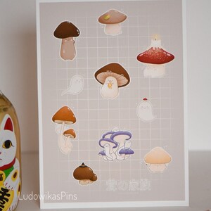 Puede incluir: Una impresi&oacute;n con una colecci&oacute;n de lindos hongos de dibujos animados con diferentes colores y dise&ntilde;os. La impresi&oacute;n tiene un fondo con patr&oacute;n de cuadr&iacute;cula y el texto "きのこの家族" en japon&eacute;s.