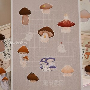 Puede incluir: Una ilustraci&oacute;n digital de una colecci&oacute;n de setas de diferentes colores y formas. Las setas est&aacute;n dibujadas en un estilo de dibujos animados y tienen caras lindas. El texto "茸の家族" est&aacute; escrito en japon&eacute;s en la parte inferior de la imagen.