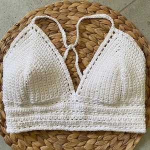 May include: White crocheted halter top with a deep V-neckline. The top is made with a simple stitch pattern and has a relaxed fit.