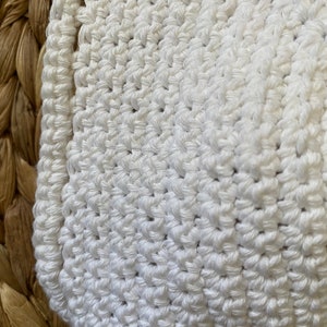 May include: White crocheted fabric with a textured pattern. The fabric is soft and has a delicate, handmade look.