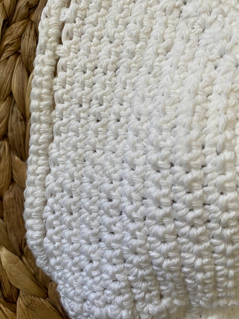 May include: White crocheted fabric with a textured pattern. The fabric is soft and has a delicate, handmade look.