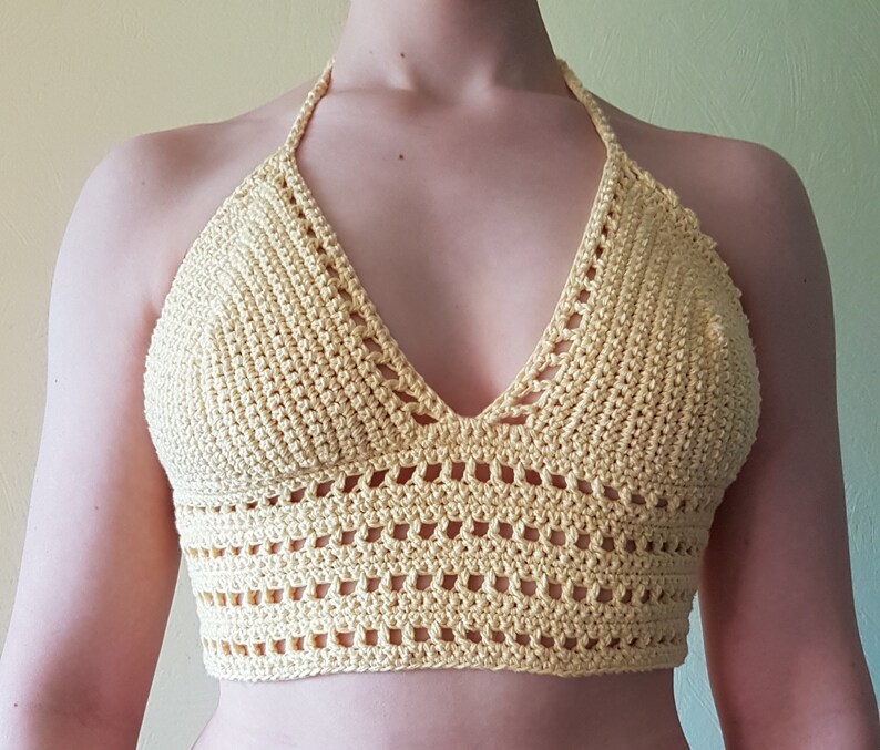 May include: A yellow crochet halter top with a V-neckline and a delicate openwork pattern.