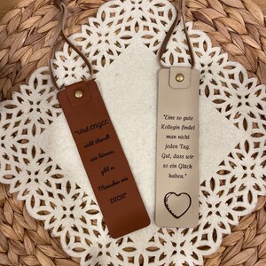 May include: Two leather bookmarks with inspirational quotes. The brown bookmark says "Weil Engel nicht &uuml;berall sein k&ouml;nnen, gibt es Menschen wie DICH". The beige bookmark says "Eine so gute Kollegin findet man nicht jeden Tag. Gut, dass wir so ein Gl&uuml;ck haben."