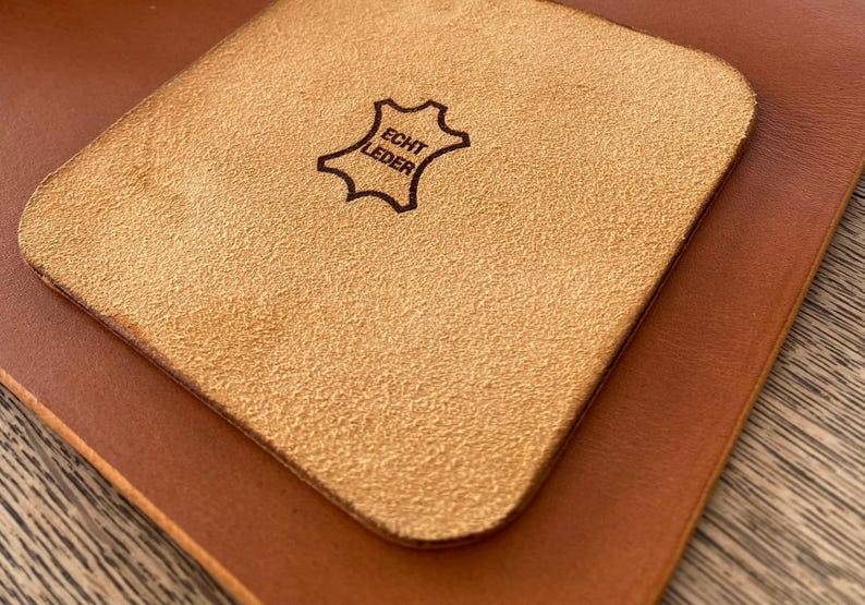 May include: A light brown leather coaster with the text "Echt Leder" in a black oval.