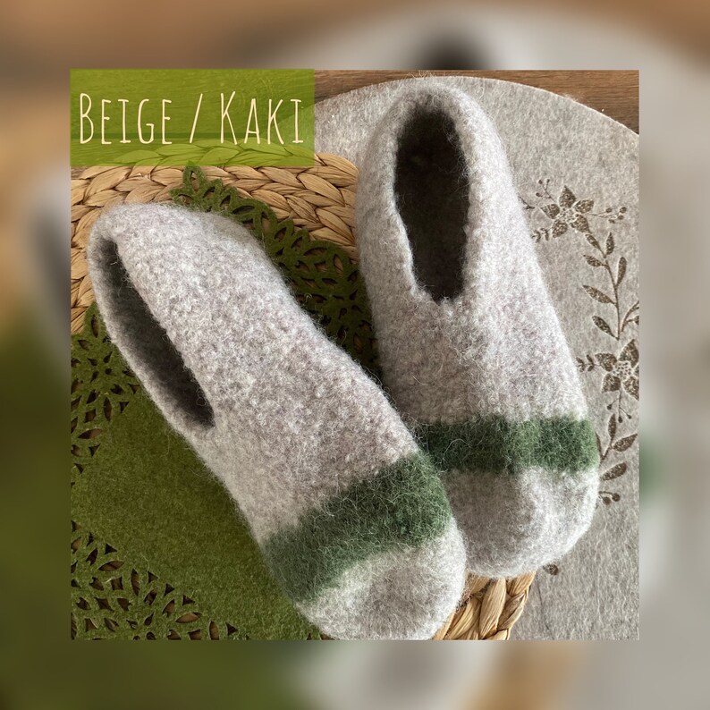 May include: Beige and green wool slippers with a contrasting stripe. The slippers are on a woven mat.