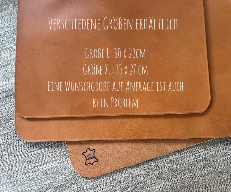 May include: A close-up of a brown leather surface with white text that reads "VERSCHIEDENE GR&Ouml;BEN ERH&Auml;LTLICH" and lists sizes in centimeters: "GROBE L: 30 X 23CM", "GROBE XL: 35 X 27 CM". The text continues: "EINE WUNSCHGROBE AUF ANFRAGE IST AUCH KEIN PROBLEM". A small black stamp with the text "ECHT LEDER" is visible in the lower right corner.