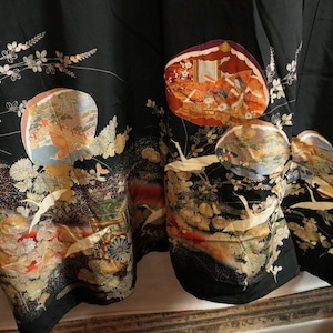 May include: Black kimono with colorful, detailed illustrations. The design includes floral patterns, birds, and scenes within circular and oval shapes. The fabric appears to be silk or a similar material.