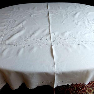 Puede incluir: Mantel ovalado blanco con detalles bordados florales y bordes festoneados. El mantel está hecho de una tela blanca suave y es adecuado para una mesa de comedor. El bordado añade un toque decorativo.