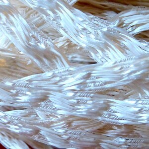May include: A close-up of white, woven fibers, creating a textured, interwoven pattern.