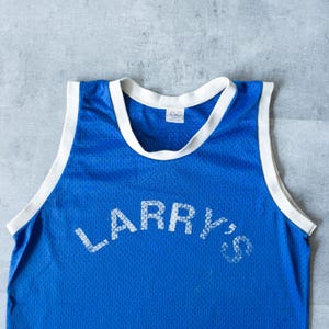 May include: A blue mesh jersey with white trim around the collar and armholes. The jersey features the name "LARRY'S" in white block letters across the front. The jersey is likely vintage or retro.