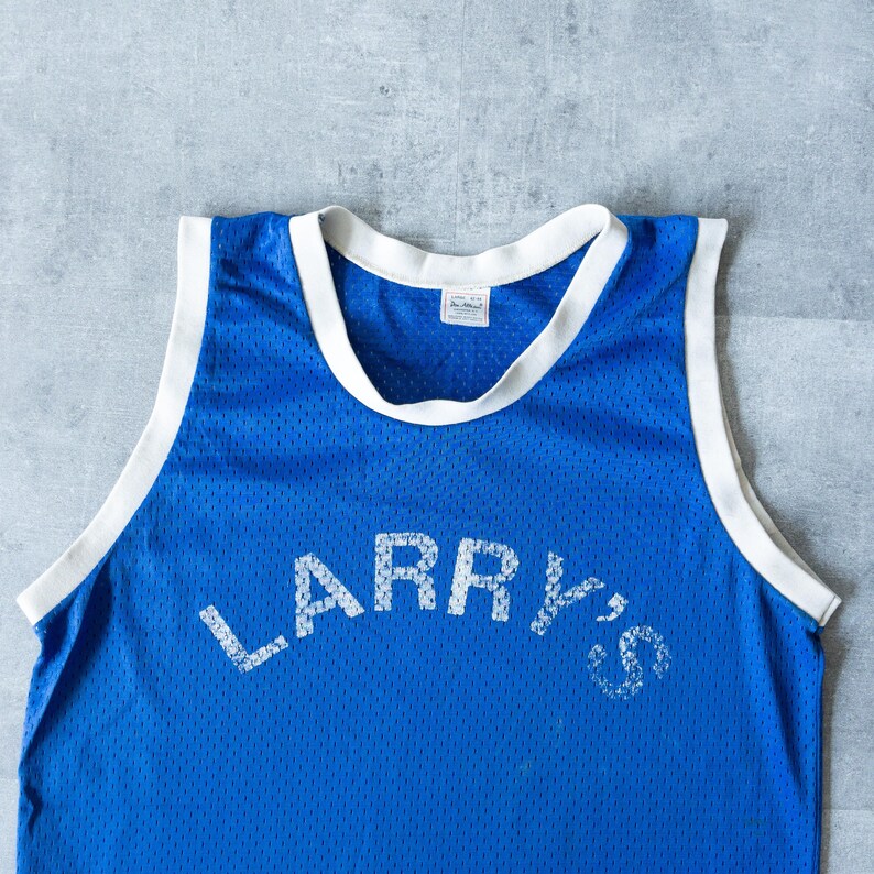 May include: A blue mesh jersey with white trim around the collar and armholes. The jersey features the name "LARRY'S" in white block letters across the front. The jersey is likely vintage or retro.