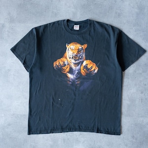 May include: Dark navy blue t-shirt with a detailed graphic of a tiger. The tiger has orange and white fur, baring its teeth and claws. The tiger is centered on the shirt, with a blue background.
