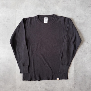 May include: A black long-sleeved thermal shirt with a crew neck and ribbed texture. The shirt has a small tag on the lower right and a label on the back of the neck. The shirt is a medium size.