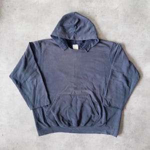 May include: A blue-grey hoodie with a front pocket and a hood. The sweatshirt is made of a soft material and has long sleeves. The hoodie is a casual garment, suitable for everyday wear.