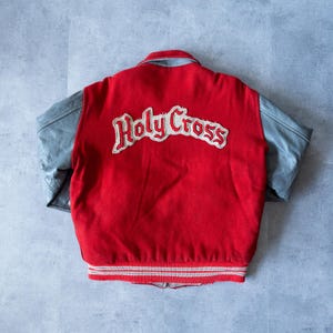 Pode incluir: Casaco de beisebol vermelho e cinza com "Holy Cross" bordado nas costas.