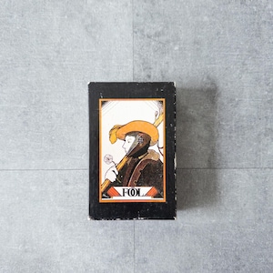 May include: A vintage book with a black cover and a colourful illustration. The illustration depicts a person in a hat and cloak, holding a staff and a flower. The word "FOL" is printed at the bottom.